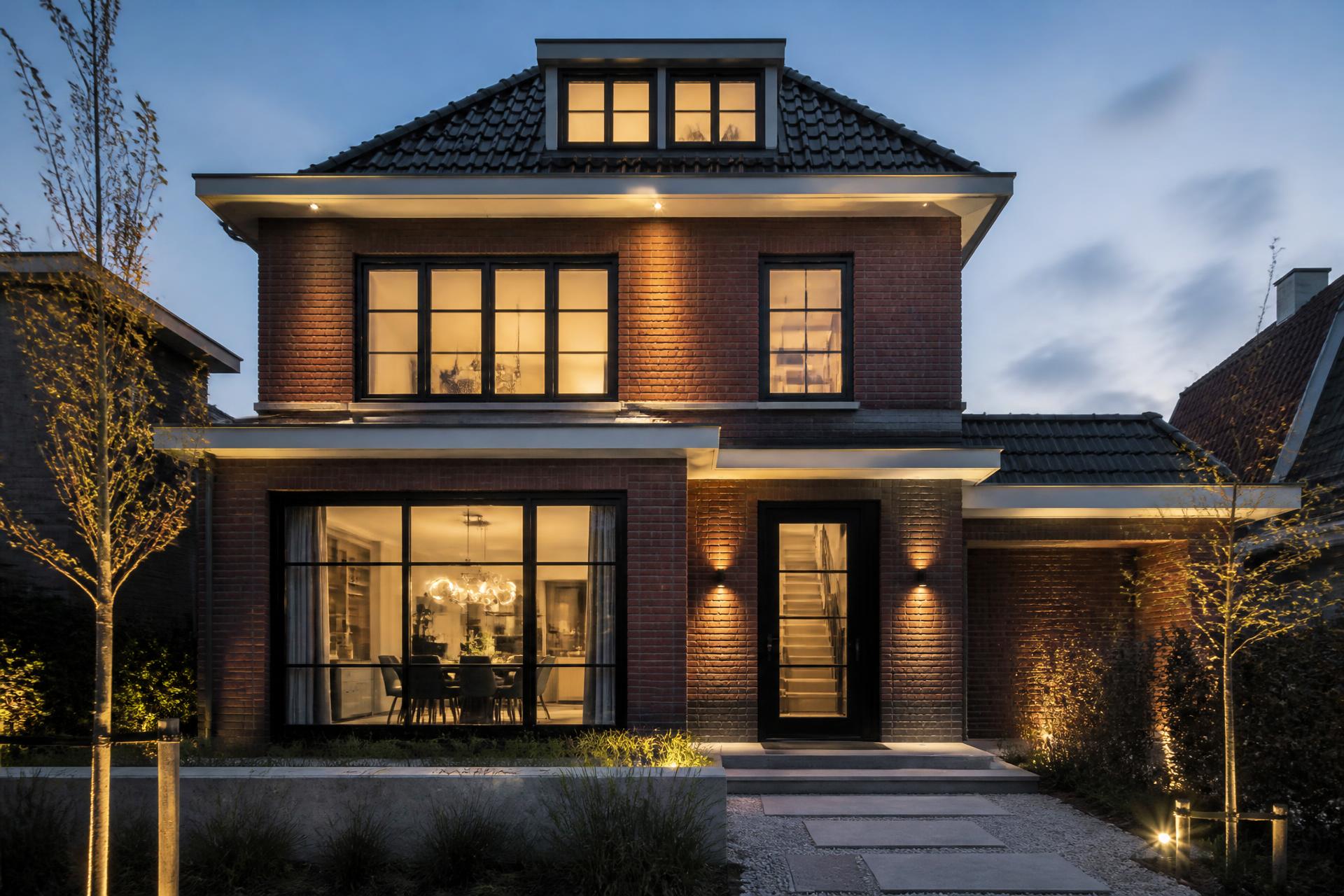Afgerond bouwproject: gerenoveerde woning met verlichte gevel in de avond